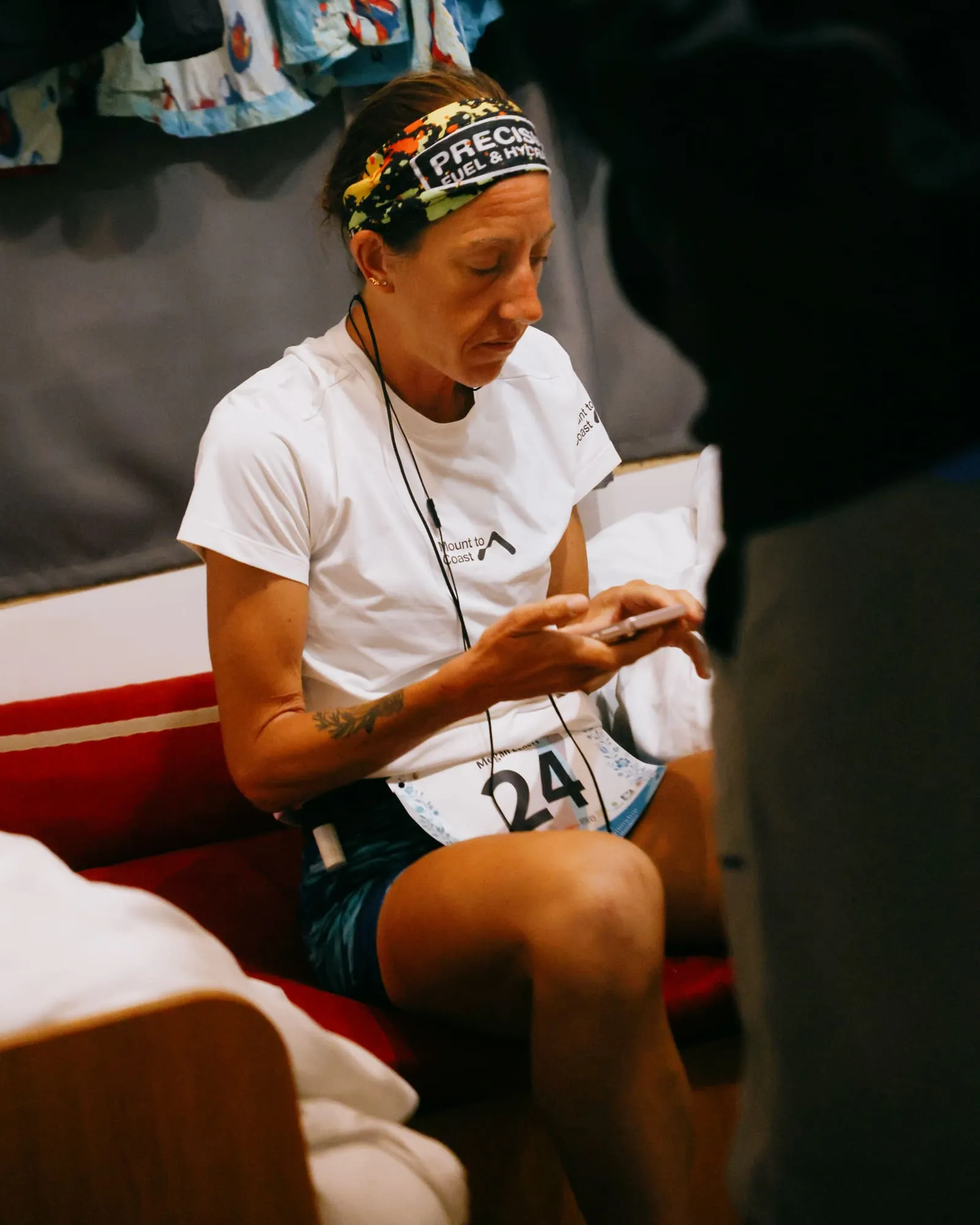 Megan Eckert, bib 24, seated on a bench checking her phone during a break at the EMU 6-Day Race
